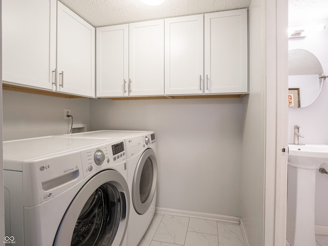 washroom featuring baseboards, cabinet space, a textured ceiling, marble finish floor, and separate washer and dryer