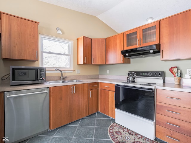 kitchen featuring a sink, under cabinet range hood, light countertops, appliances with stainless steel finishes, and dark tile patterned flooring