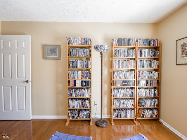 unfurnished room featuring a textured ceiling, baseboards, and wood finished floors