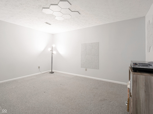 carpeted empty room featuring visible vents, baseboards, and a textured ceiling