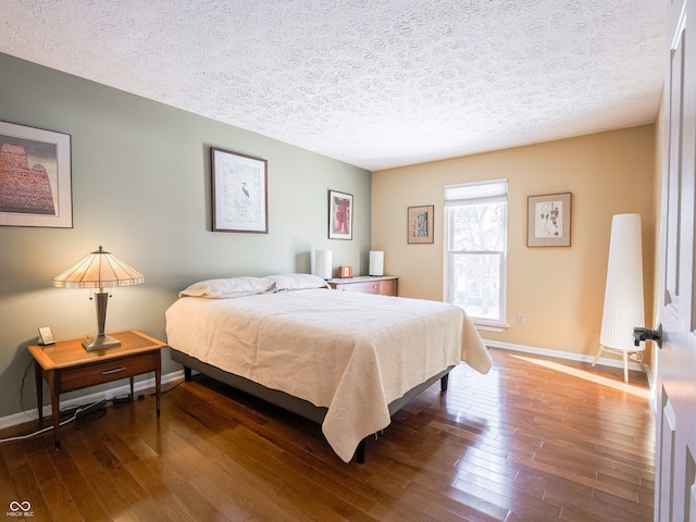 bedroom featuring baseboards, wood-type flooring, and a textured ceiling