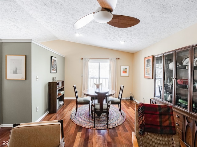 dining area featuring lofted ceiling, wood finished floors, a ceiling fan, and baseboards