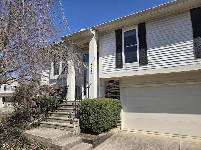 view of exterior entry with concrete driveway, a garage, and brick siding