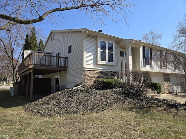 view of property exterior featuring driveway, a yard, an attached garage, a wooden deck, and brick siding