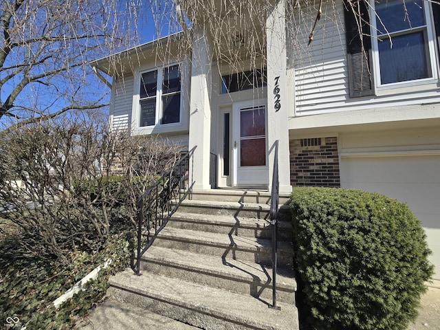 view of exterior entry with a garage and brick siding