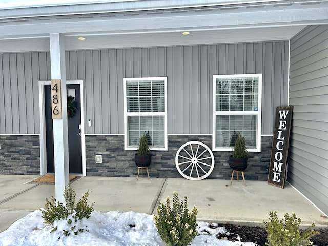 snow covered property entrance with a porch