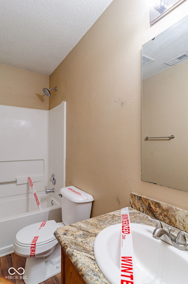 full bathroom featuring a textured ceiling, toilet, wood-type flooring, shower / washtub combination, and vanity