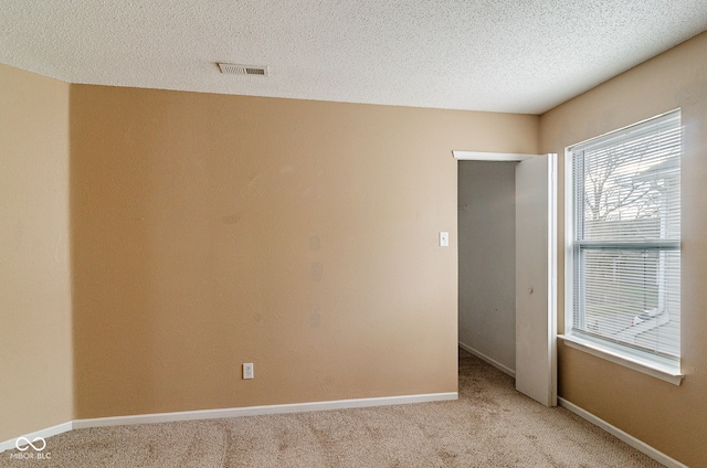 carpeted spare room with a textured ceiling