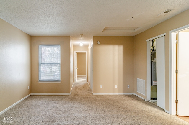 unfurnished room with a textured ceiling and light carpet