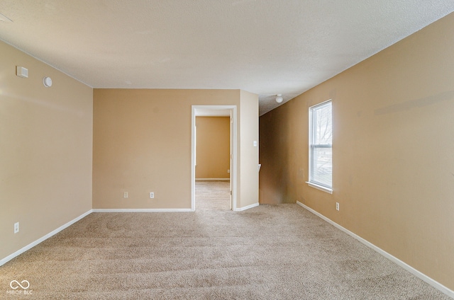 spare room featuring a textured ceiling and light carpet