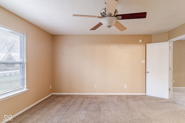 spare room with a textured ceiling, ceiling fan, and light colored carpet