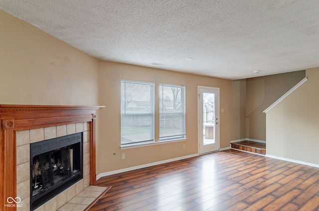 unfurnished living room with a fireplace, a textured ceiling, and wood-type flooring