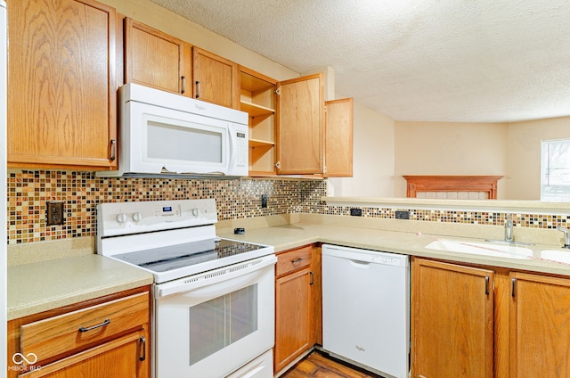 kitchen featuring white appliances, backsplash, sink, and a textured ceiling