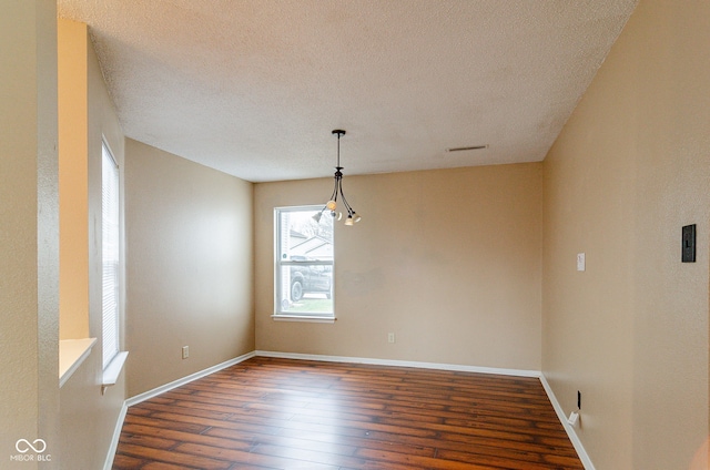 unfurnished room with a textured ceiling and dark wood-type flooring