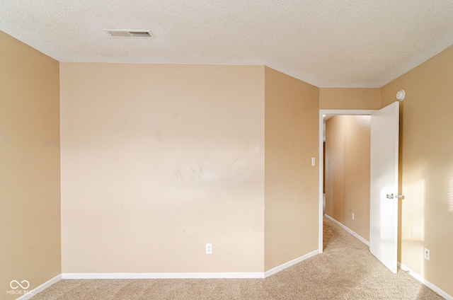 empty room featuring a textured ceiling and light carpet