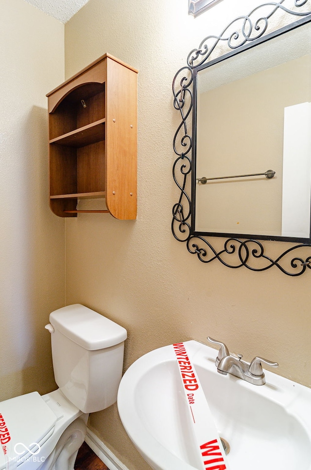 bathroom with toilet, a textured ceiling, and sink