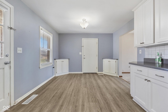 interior space featuring tasteful backsplash, light hardwood / wood-style flooring, and white cabinets