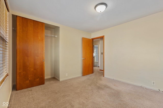 unfurnished bedroom with a closet and light colored carpet