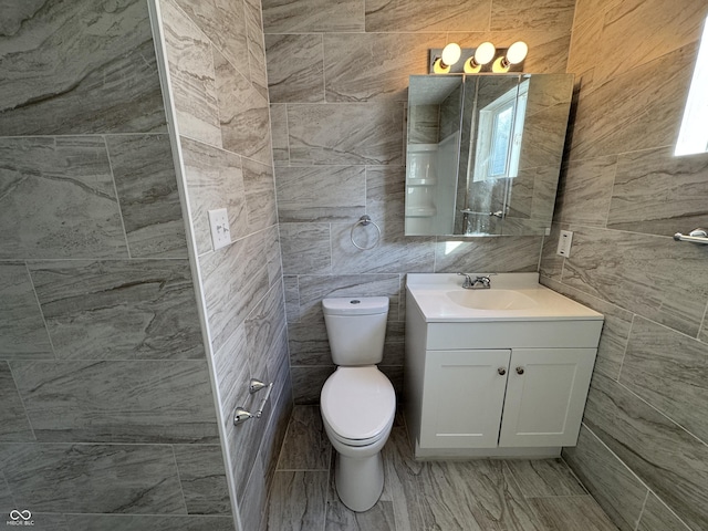 bathroom featuring vanity, toilet, and tile walls