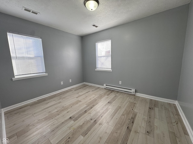 unfurnished room with light wood-type flooring, a textured ceiling, and a baseboard heating unit