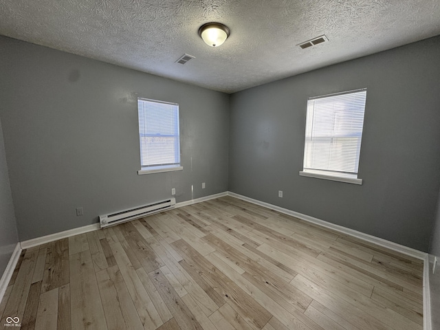 empty room with a textured ceiling, light hardwood / wood-style flooring, and a baseboard radiator