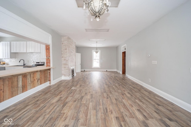 unfurnished living room featuring a chandelier, light hardwood / wood-style flooring, and sink