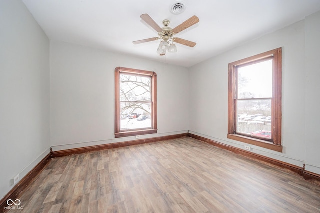 empty room featuring a wealth of natural light, hardwood / wood-style floors, and ceiling fan