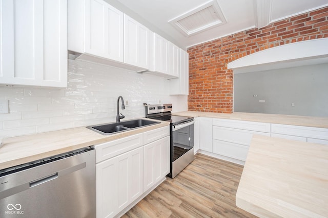 kitchen with sink, white cabinets, brick wall, and appliances with stainless steel finishes