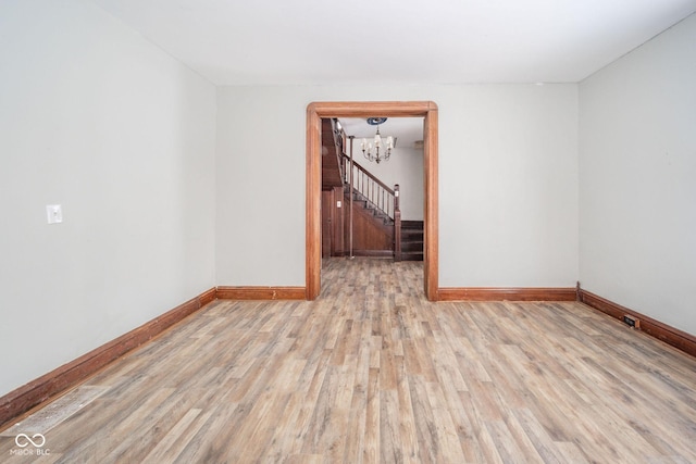 empty room with a chandelier and light hardwood / wood-style floors