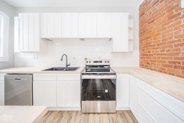 kitchen with decorative backsplash, appliances with stainless steel finishes, sink, white cabinets, and light hardwood / wood-style floors