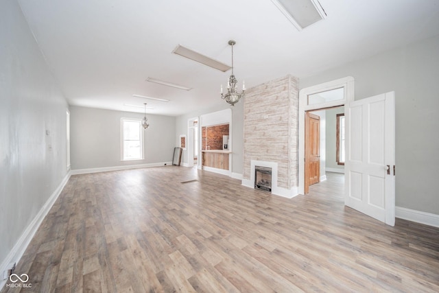 unfurnished living room with light hardwood / wood-style flooring and a stone fireplace