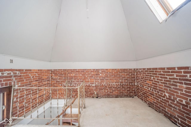 bonus room with vaulted ceiling with skylight and brick wall