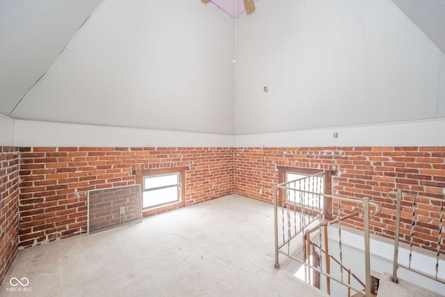 additional living space featuring brick wall and lofted ceiling