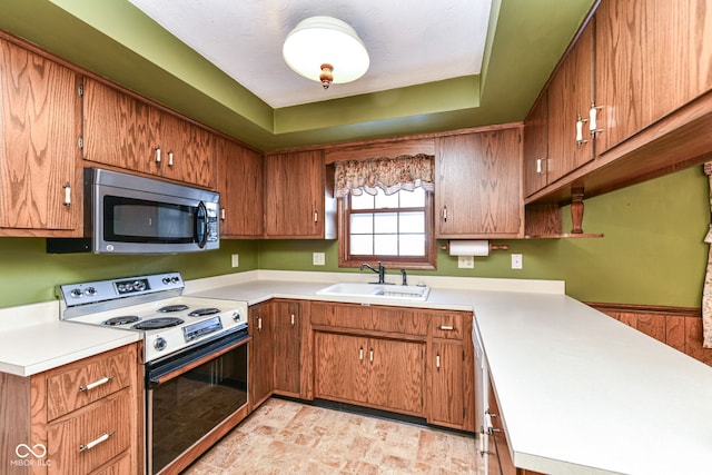 kitchen with wood walls, a raised ceiling, sink, and appliances with stainless steel finishes