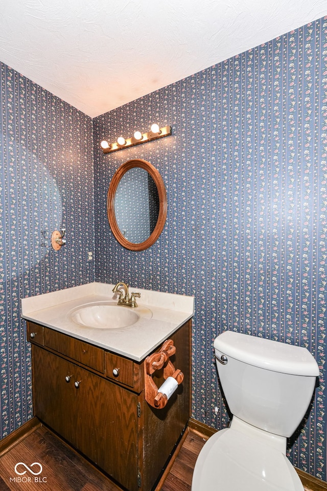 bathroom featuring hardwood / wood-style flooring, vanity, toilet, and a textured ceiling