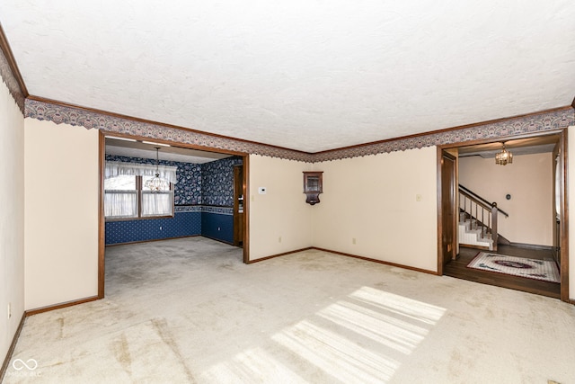 empty room with crown molding, carpet floors, a textured ceiling, and an inviting chandelier