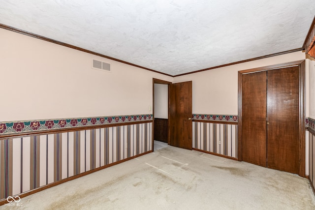 carpeted empty room featuring a textured ceiling and crown molding