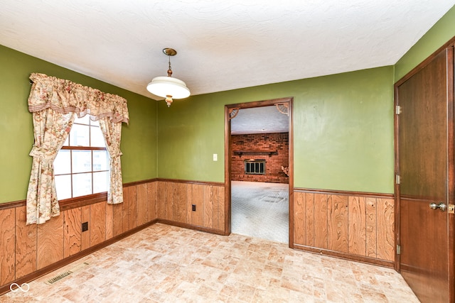 spare room with a textured ceiling and a brick fireplace