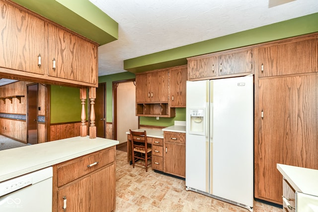 kitchen with a textured ceiling, white appliances, and built in desk