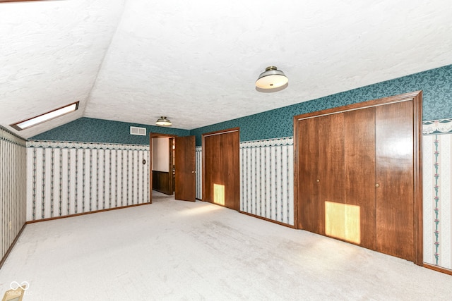 bonus room featuring light colored carpet, a textured ceiling, and vaulted ceiling