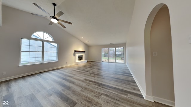 unfurnished living room featuring a wealth of natural light, hardwood / wood-style floors, ceiling fan, and lofted ceiling