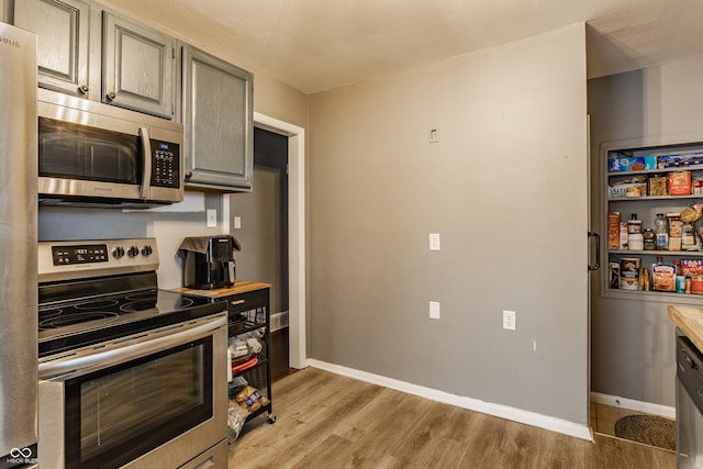 kitchen featuring appliances with stainless steel finishes, light hardwood / wood-style flooring, and gray cabinetry