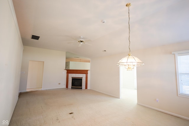 unfurnished living room with light carpet, a fireplace, ceiling fan with notable chandelier, and vaulted ceiling