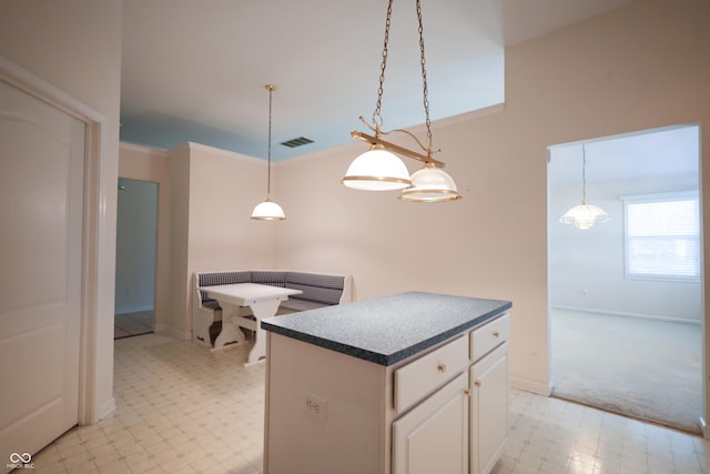 kitchen featuring decorative light fixtures, a kitchen island, white cabinetry, and crown molding