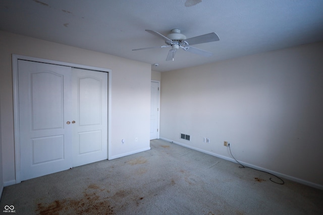 unfurnished bedroom featuring ceiling fan, a closet, and light carpet