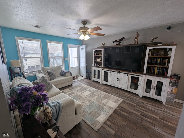 living room with ceiling fan, dark wood-type flooring, a healthy amount of sunlight, and a textured ceiling