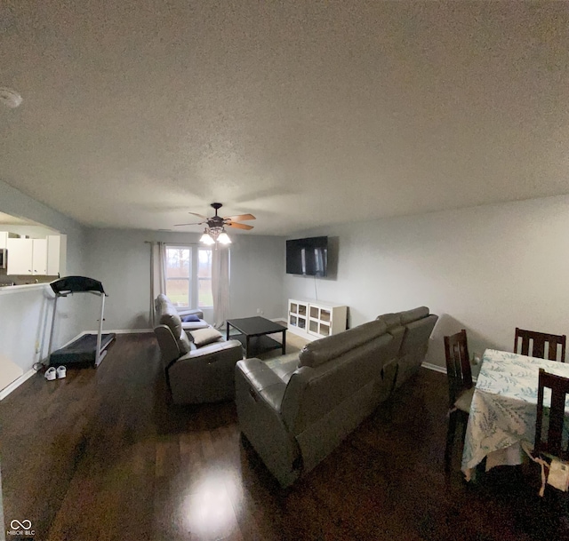 living room with ceiling fan, dark hardwood / wood-style flooring, and a textured ceiling