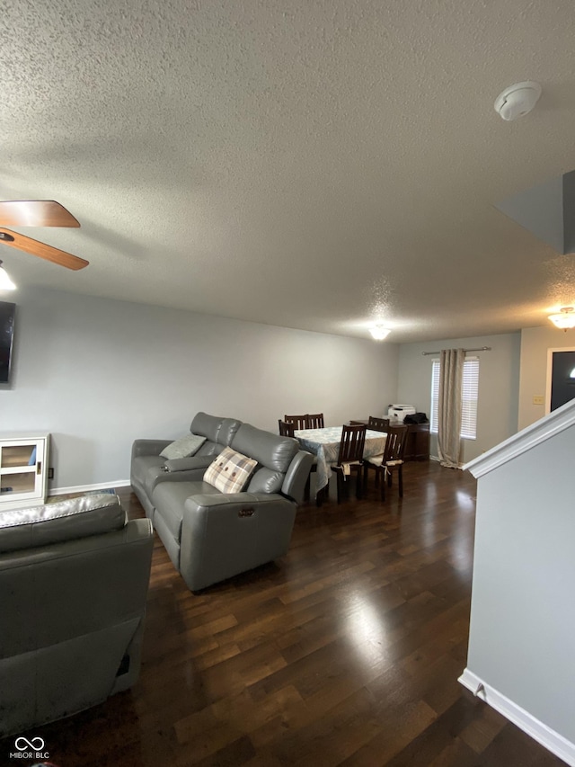 living room with ceiling fan, dark hardwood / wood-style flooring, and a textured ceiling