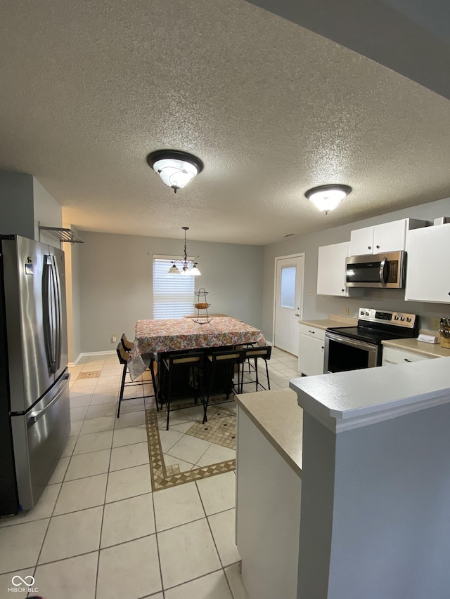 kitchen featuring pendant lighting, white cabinets, light tile patterned floors, appliances with stainless steel finishes, and kitchen peninsula