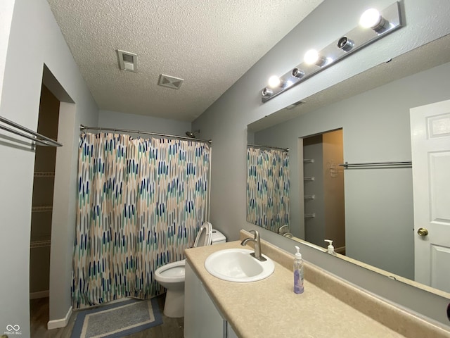 bathroom featuring a textured ceiling, vanity, toilet, and walk in shower